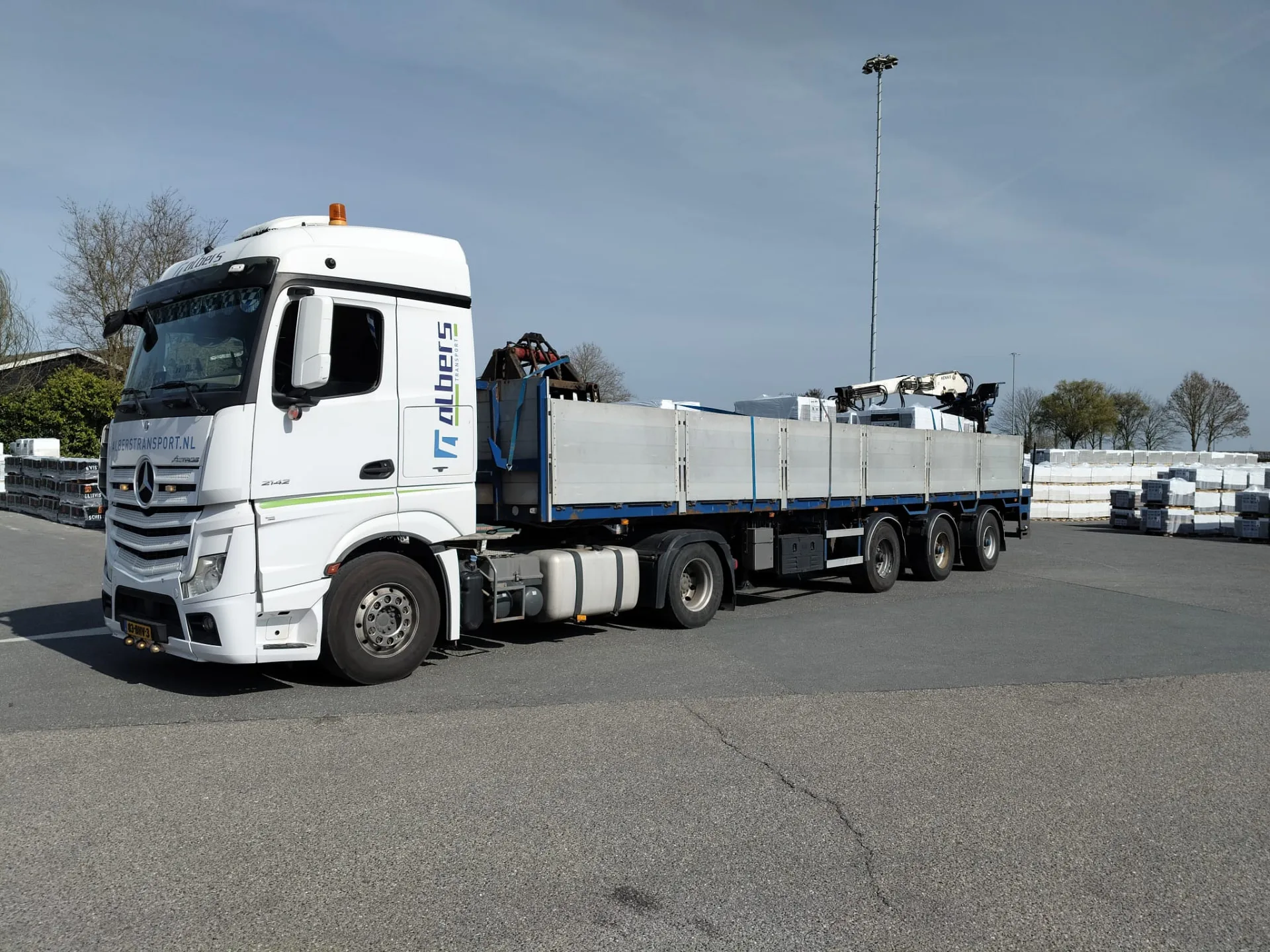 Witte Mercedes Actros van Albers Transport met beladen oplegger op het terrein